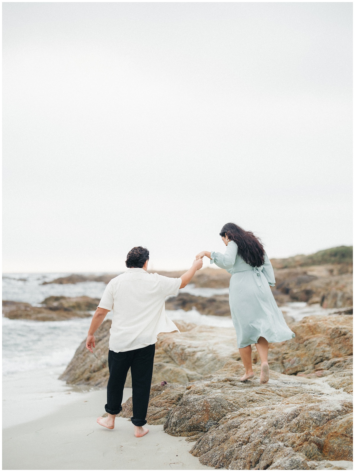Boyfriend leading his girlfriend on rocks in Pacific Grove during their engagement session